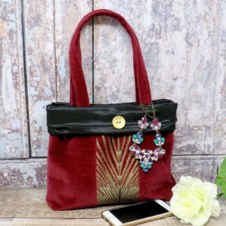 Burgundy velvet evening bag with a black satin trim and a decorative centre panel.
