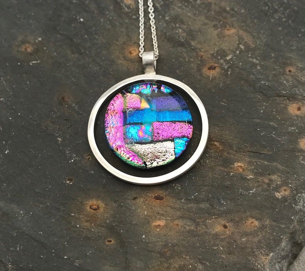 Mosaic dichroic glass circle within an eco-silver circle pendant.