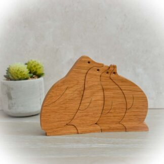 Handcrafted Oak penguin family of four nestling together