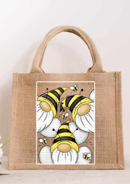 Small natural jute tote bag featuring a bright illustration of three gnomes in yellow and black striped bumblebee hats with small bees flying around them.