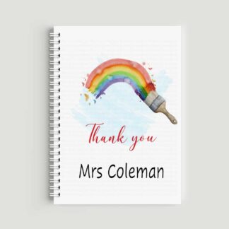 A spiral-bound A5 notebook with a watercolor illustration of a paintbrush creating a bright rainbow arc. The text "Thank you Mrs Coleman" is printed on the front in red and black lettering.