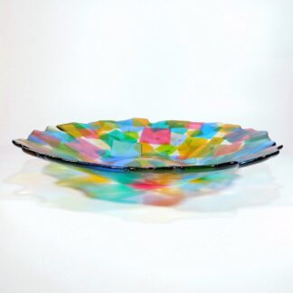 A large fused glass bowl made with a multitude of square coloured glass pieces overlapping each other.