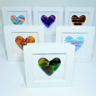 A selection of fused glass hearts in various colours mounted in a small box frame