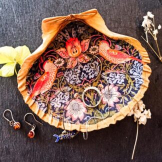 Extra large scallop shell gilded, trinket dish, decoupaged with the red birds from William Morris Strawberry Thief. The scallop shell is placed on a dark surface surrounded by jewellery and small dried flowers