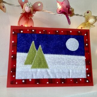 Christmas card in fabric with two trees and moon against a snowy background