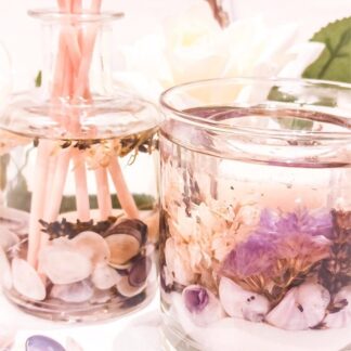Lavender luxury botanical gift set. Scented reed diffuser and soy and gel wax scented candles containing purple shells and dried flowers are shown in close up