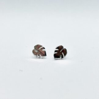 Silver monstera leaf earrings on a white background