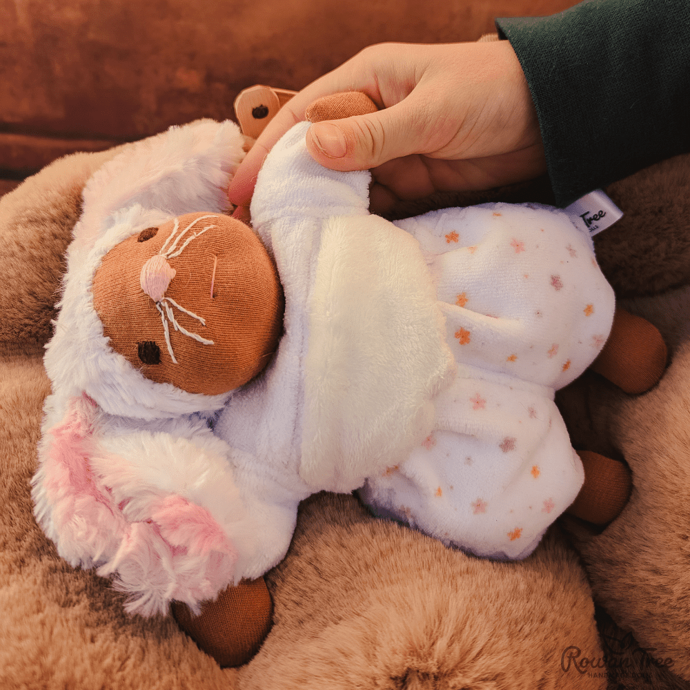 child hand with green sleeve holding little white mouse doll hand