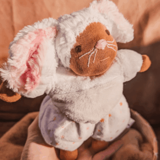little white mouse doll with pink nose and brown skin balancing on a hand with a brown background