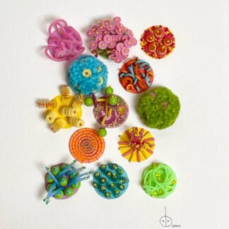 Beaded, embroidered collage, a mix of orange, lime, turquoise and pink. Unusual items stitched onto water coloured paper such as silicone, tubing and pom-poms.