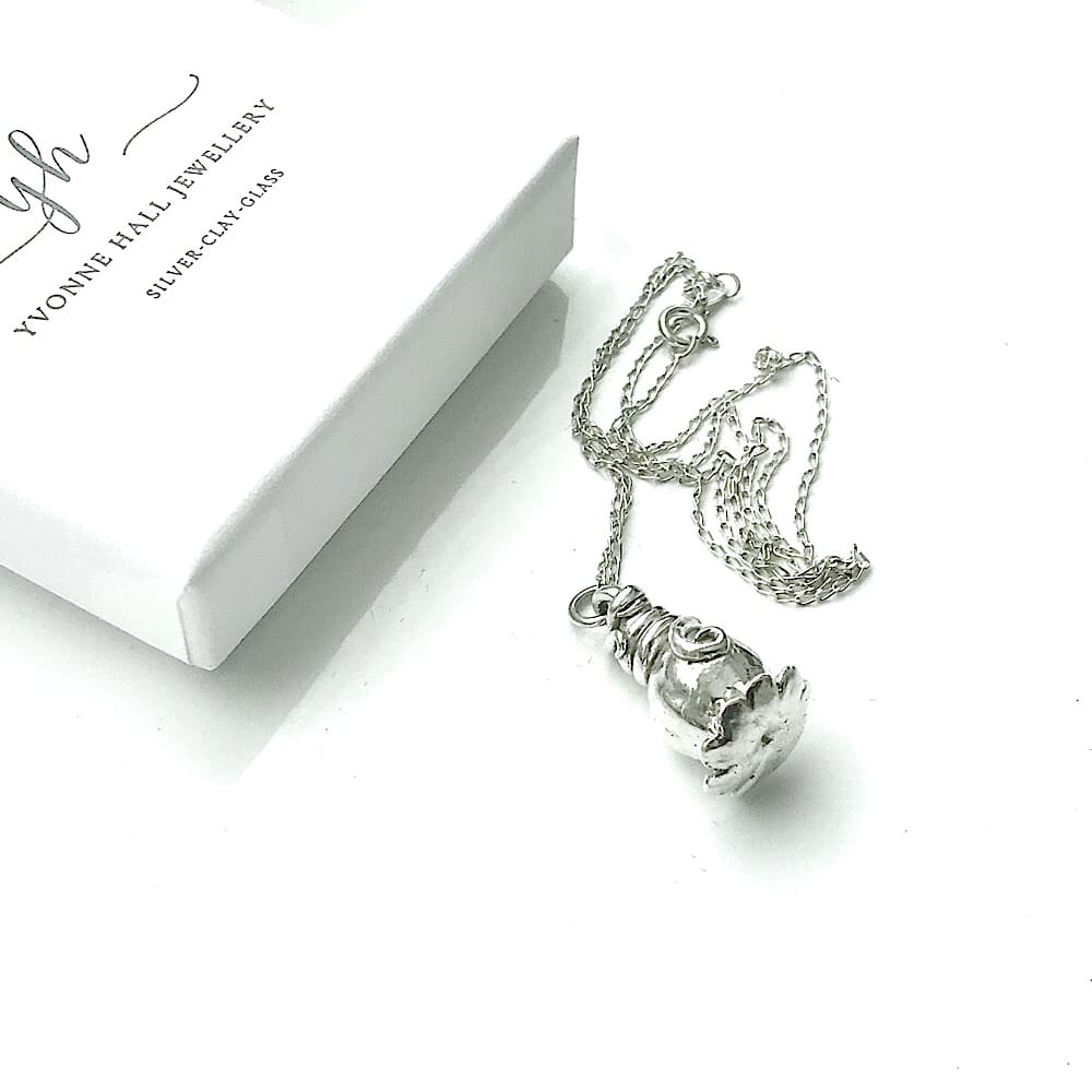 A fine silver poppy sede head with a sterling silver chain. The pendant is displayed on a white background with a small white presentation box in the top left corner.