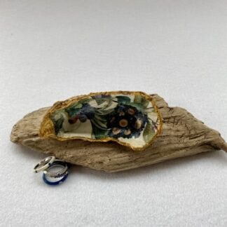 A handcrafted Decoupaged Oyster Shell Featuring an aricular in blue