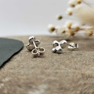 Pair of handcrafted recycled sterling silver cluster bead stud earrings displayed hanging on decorative stone