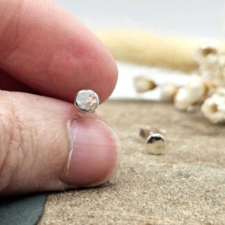 Handcrafted recycled oxidised sterling silver hammered 4.5mm round stud earrings held between jeweller's fingers