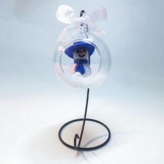 Handmade needle-felted snowman glass bauble with a black stand, featuring a blue hat and scarf in a snowy globe.