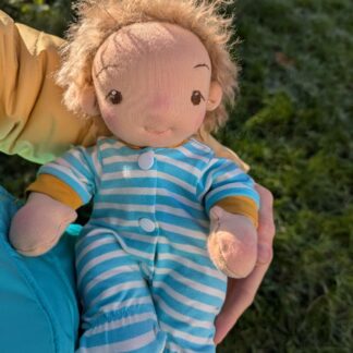 Handmade fabric baby boy doll in a onesie outdoors held in a woman's arms