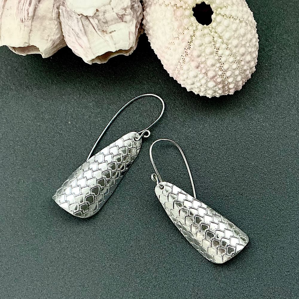 A pair of handmade large fine silver clay drop,earrings with a textured pattern. They have sterling silver ear wires and are displayed on a dark grey background.