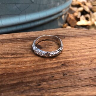 A recycled sterling silver ring featuring an organic rocky texture, created through the lost wax casting method.