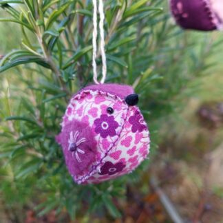 a handstitched felt and fabric bird decoration in shades of pink and purple.
