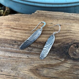 Recycled silver drop earrings textured with cuttlefish and displayed on wood