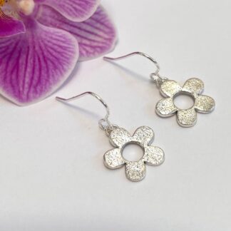 Handmade silver daisy flower earrings attached to ear hook