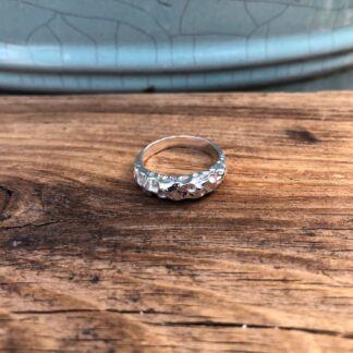 A recycled sterling silver ring featuring a deep , natural, organic boulder texture.