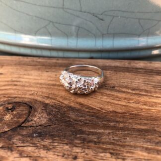 A recycled sterling silver ring featuring a unique, organic barnacle texture