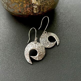 A pair of fine silver drop earrings in a round shirlie shape with sterling silver ear wires. They are dusplayed on a dark grey background.