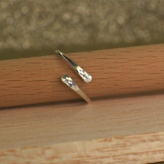 Sterling silver wrap ring with hammered ends shown on display stand