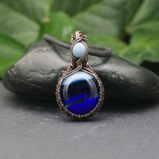 Handmade copper wire-wrapped pendant featuring a blue glass cabochon, crafted with intricate wire weaving and an oxidised finish.