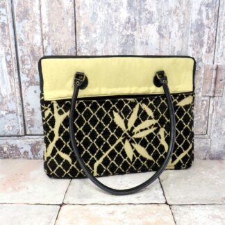 A small laptop carry case in black and gold and with black leather handles.