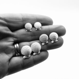 silver scallop shell earrings held in a hand