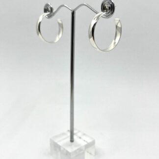 A pair of medium size sterling silver hoop earrings with post and scroll butterfly fittings, displayed on a stand with a white background.