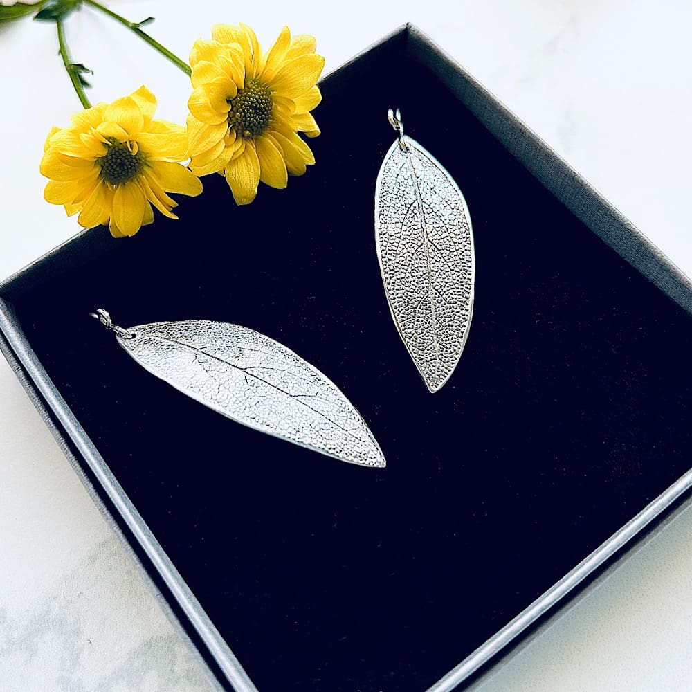 Fine silver clay sage leaf drop earrings with sterling silver ear wires. Displayed on a black velvet pad in a presentation box.