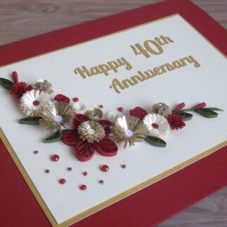 A handmade ruby 40th wedding anniversary card decorated with quilled flowers in red, cream and gold