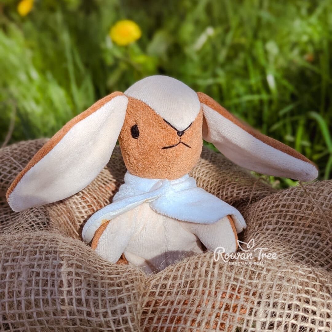 Caramel and cream lop eared handmade velveteen bunny sat on hessian sacking in a plant pot.
