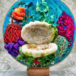 8" Embroidery Hoop of a 3d felted clam shell with a pearl in the center