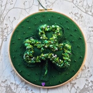 A green felt beaded shamrock on a 8" embroidery hoop