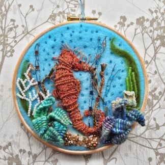 A stumpwork weaved seahorse mounted on a 7" embroidery hoop