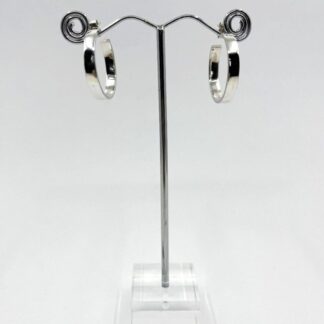 Sterling silver shiny hoop earrings displayed on a metal stand on a white background