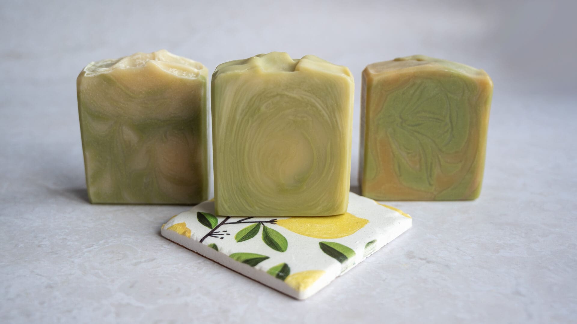 Green and yellow soap bars sitting on a citrus lemon tile
