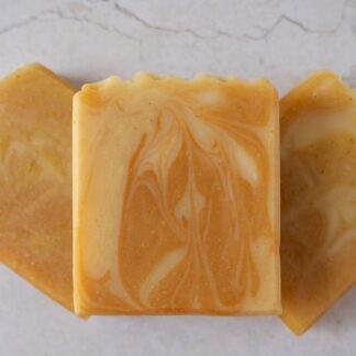 orange soap bars arranged one on top of the other. they have a nice doal shade twirl design
