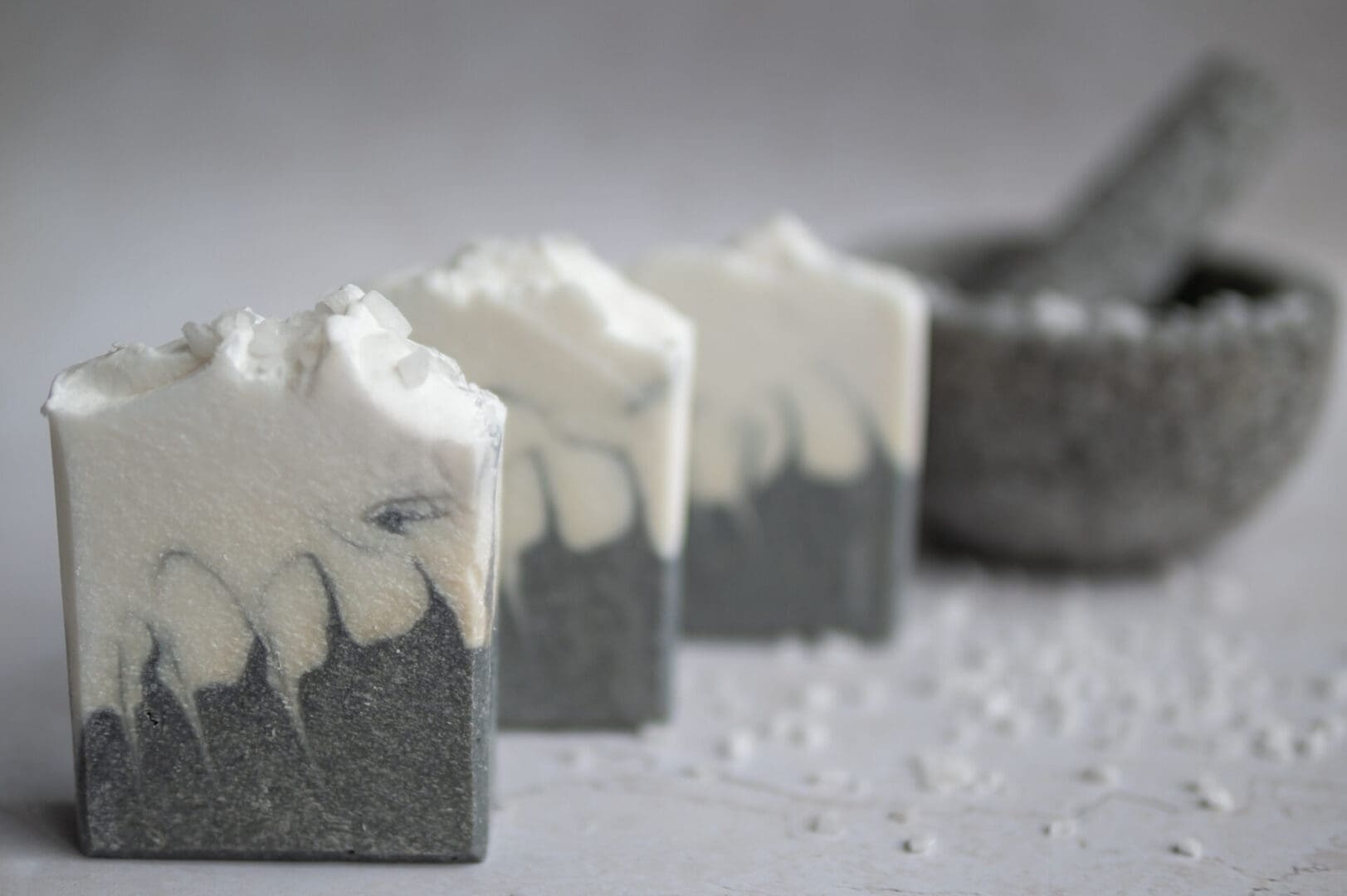 White and grey patterened soap bar sitting on a white surface with sea salt