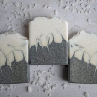 White and grey patterened soap bar sitting on a white surface with sea salt