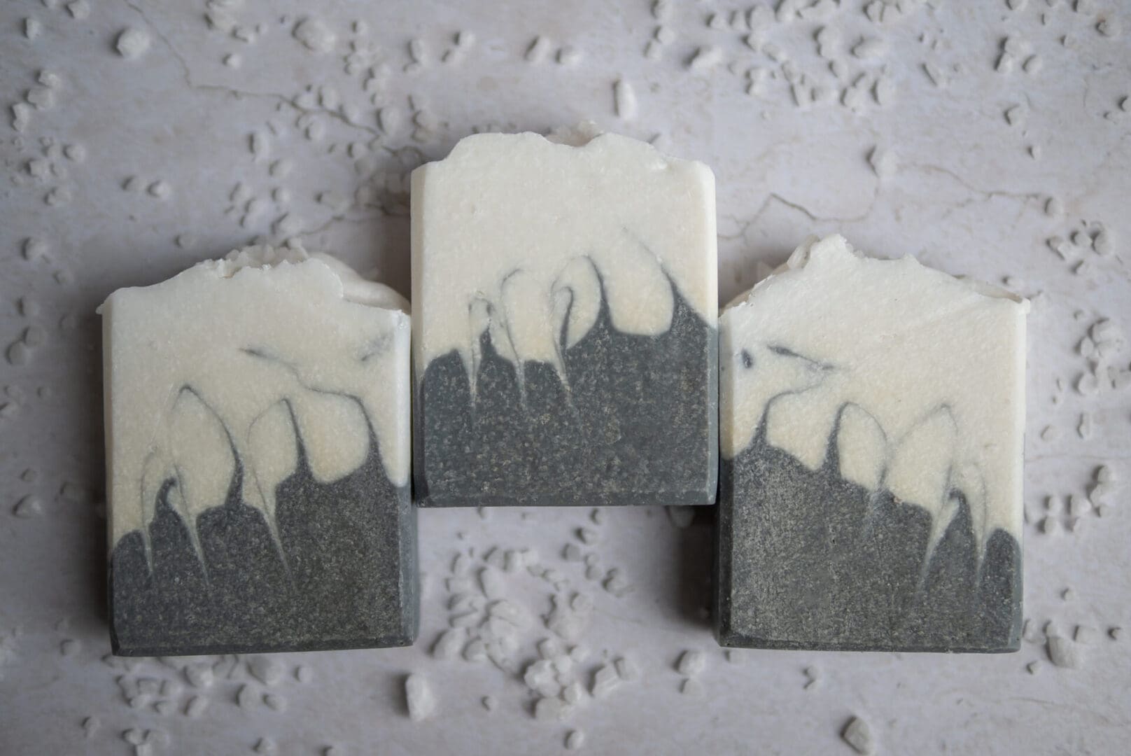 White and grey patterened soap bar sitting on a white surface with sea salt