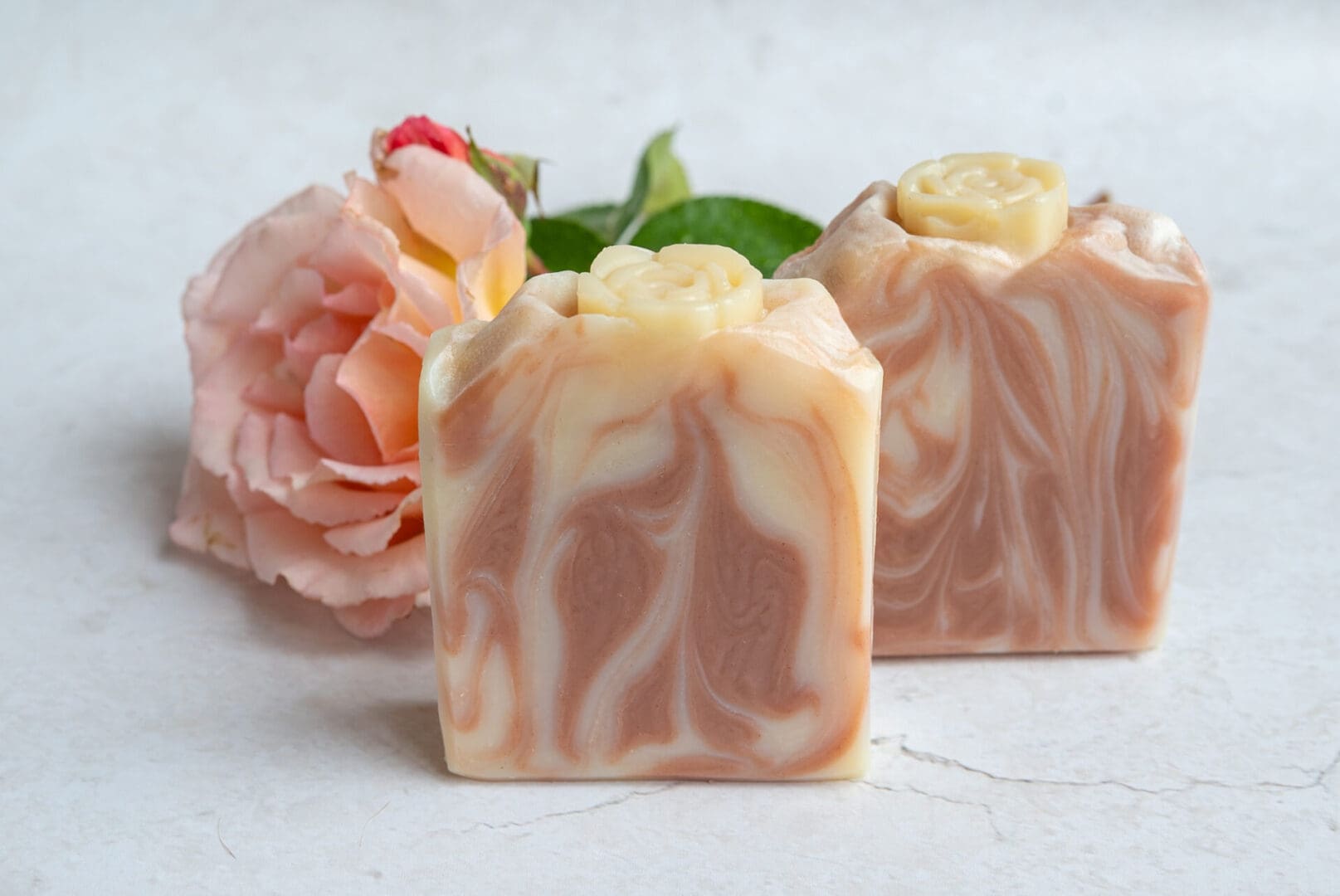 dark pink and white soap bars sitting in front of a pink rose