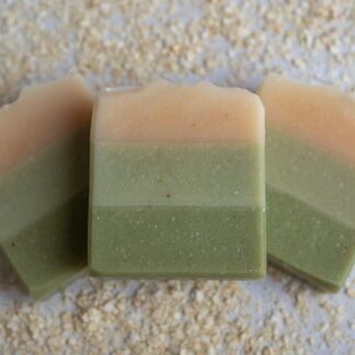 Green layered soap bars sitting on a bed of oats