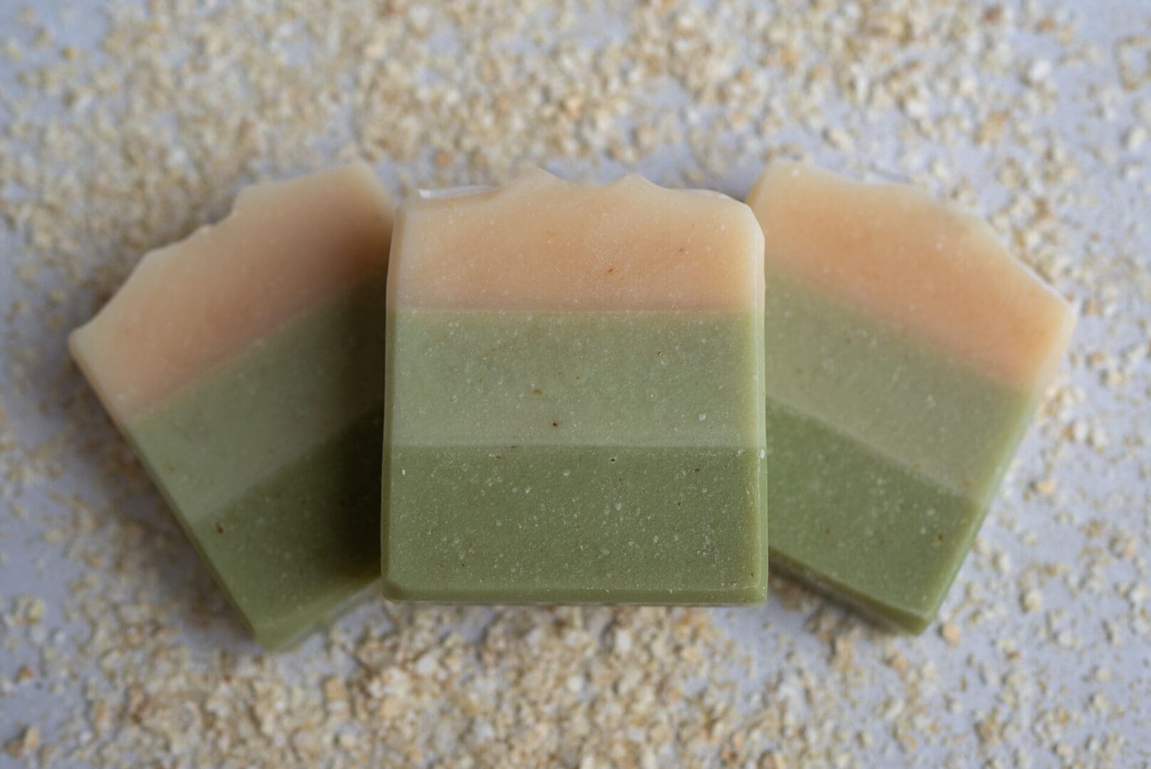 Green layered soap bars sitting on a bed of oats