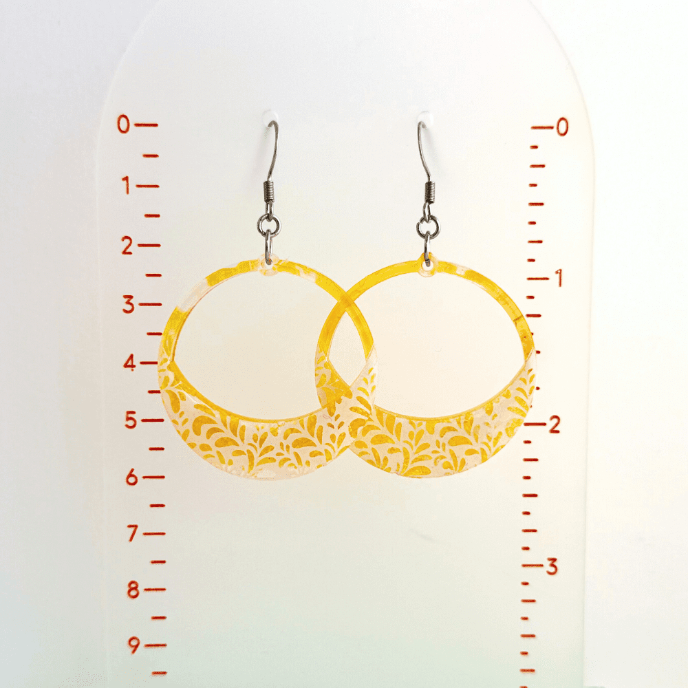 Bold yellow resin hoop earrings with floral lace detailing on hypoallergenic surgical steel earring hooks
