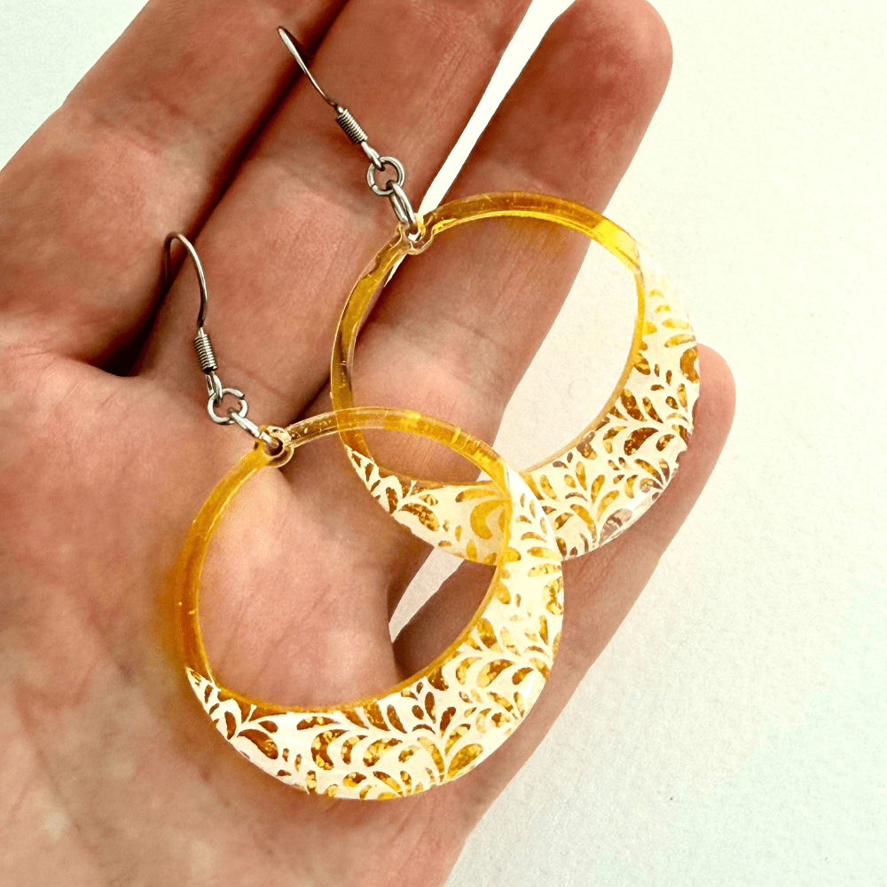 Bright yellow hoop earrings with floral lace detailing on hypoallergenic surgical steel earring hooks